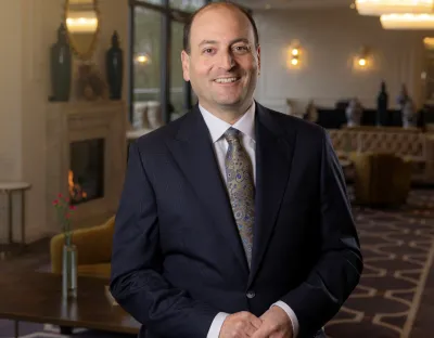 A photo of a man in formal dress standing in an ornately decorated room