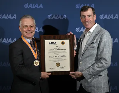 Man being presented with certificate by another man in award ceremony setting