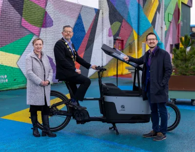 A picture of three people standing beside a large e-bike - they are Irene Ward, Mayor John Moran and James Green