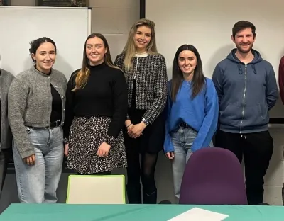 9 people standing at the front of a classroom