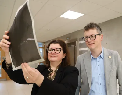 A picture of two UL academics looking at a sheet of carbon fibre