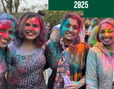 4 smiling students with Holi colours all over them