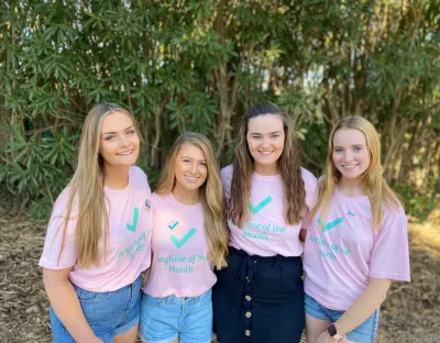 Four female UL students wearing pink Anytime of the Month branded T-shirts