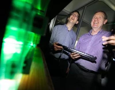 Two men holding a computer keyboard while smiling at something off-camera