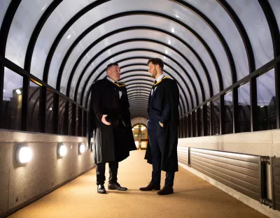 Two students in graduation robes talking