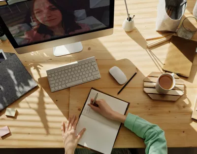 Image depicting  a work desk with notepad, coffee, keyboard, mouse and a computer screen.