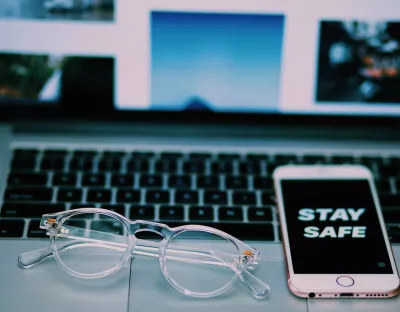 Image depicting a pair of glasses and a phone resting on a computer keyboard.