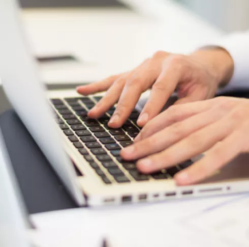 A person's hands are typing on the keyboard of a laptop