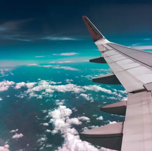 Photo of the view from a plane in the sky - the left wing is visible