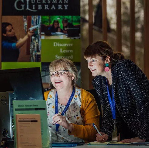 2 Library staff members collaborating over a computer screen