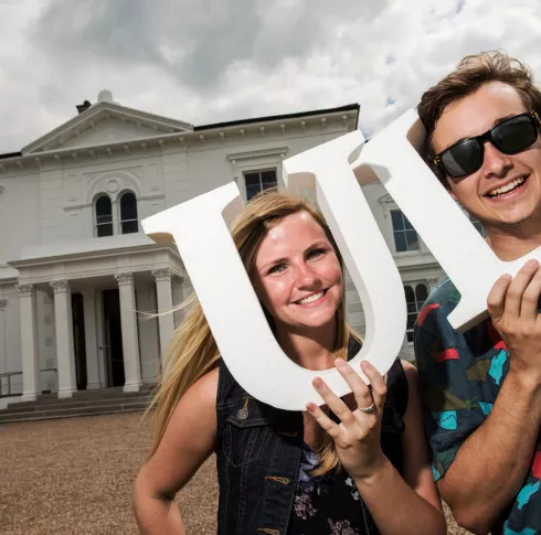 2 happy students holding UL letters