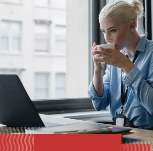 Girl drinking coffee while looking at laptop