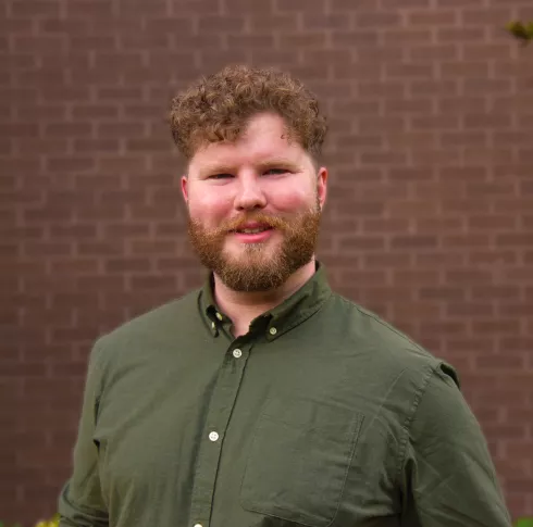 A an with a beard and curly hair smiling