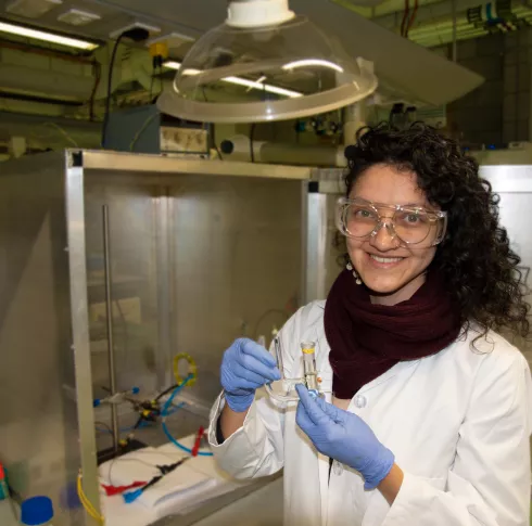 A woman with brown curly hair holding a medical device in a lab