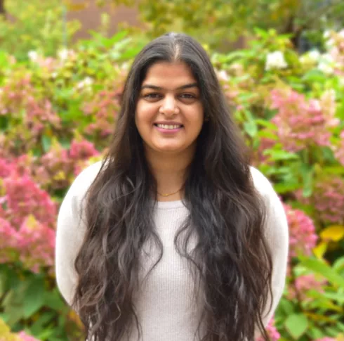 A woman with long wavy dark hair smiling outside