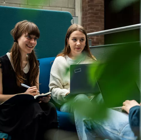 two female students studying and smiling on a couch