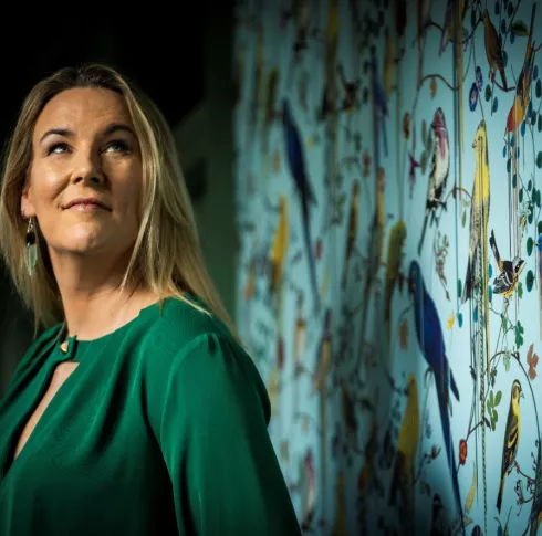 Portrait of Hannah Wrixon standing in front of vibrant wallpaper