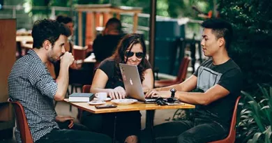 Students sitting around a table with a mac