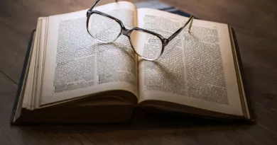 Image shows book on a table with some glasses 