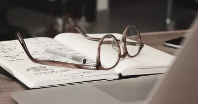 Reading glasses sitting on a notebook with a pen