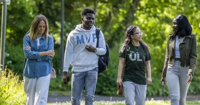 four students walking through wooded area