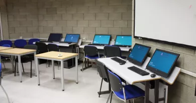 Several computers set up at desks against a grey block wall