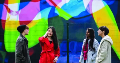 four students standing in front of wall mural