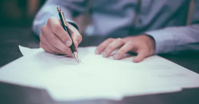 Person wearing shirt writing on sheets of paper