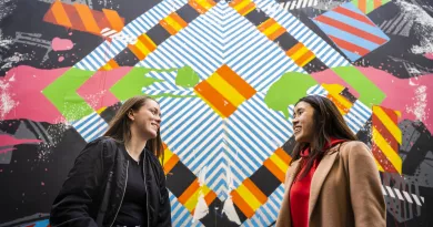 2 students standing in front of colourful mural in Limerick city