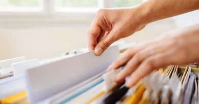 Hands are shown searching through a stack of files in a drawer