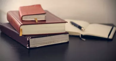 pile of three books with open notebook in background