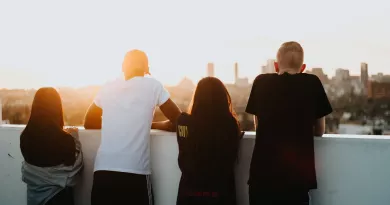 Group of young people looking out over wall with backs turned to camera