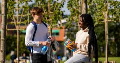 two students standing under trees and chatting