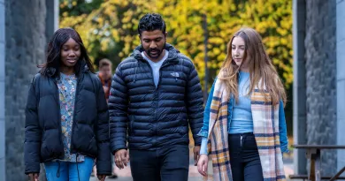 Two female and one male student walking on campus together, with yellow autumn leaves in the background.