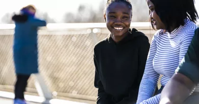 Two female students smiling and talking, while sitting on the UL Living Bridge