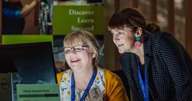 2 Library staff members collaborating over a computer screen