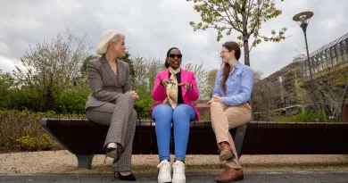 Three women sitting on a stone bench in conversation