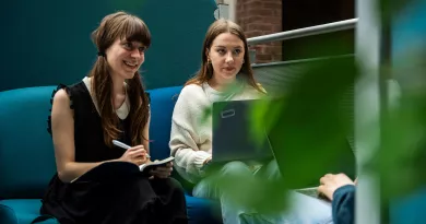 two female students studying and smiling on a couch