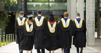 Seven graduates walking away in their robes