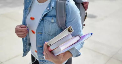 woman wearing denim jacket holding books