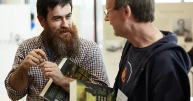 Two researchers holding books and smiling at one another