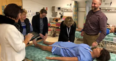 a team of men and women over a dummy patient over a hospital bed