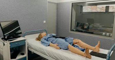 Simulation of patient dummy lying in a hospital bed beside computer