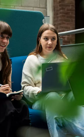 two female students studying and smiling on a couch