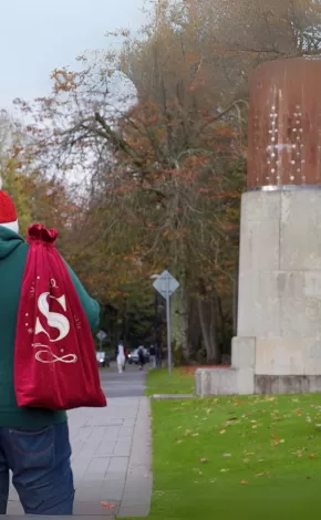 Person carrying a red sack walking near the University of Limerick sign.