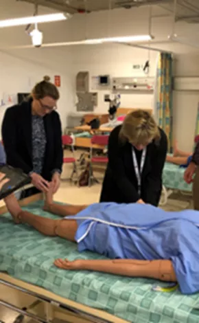 a team of men and women over a dummy patient over a hospital bed