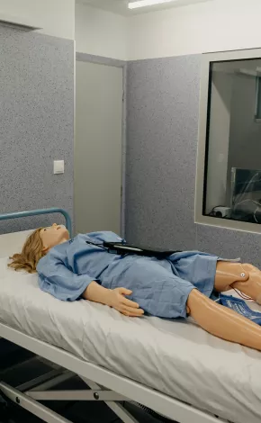 Simulation of patient dummy lying in a hospital bed beside computer