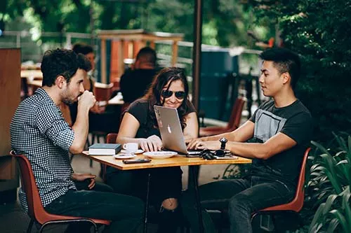 Students sitting around a table with a mac