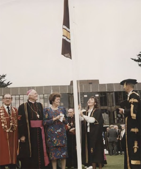 Maura Adshead, SU President, raises the flag at the inauguration of the University