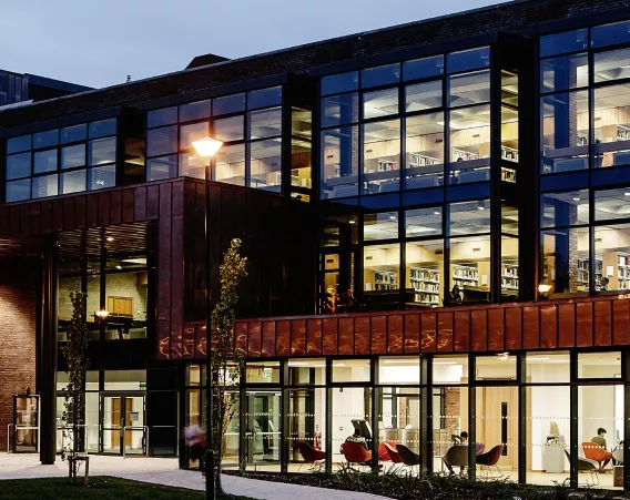 Library building lit up at evening with people